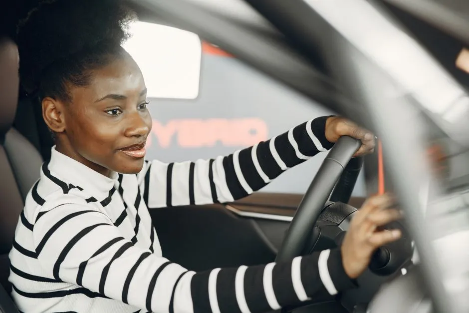 A smiling adult student at the steering wheel of a training car