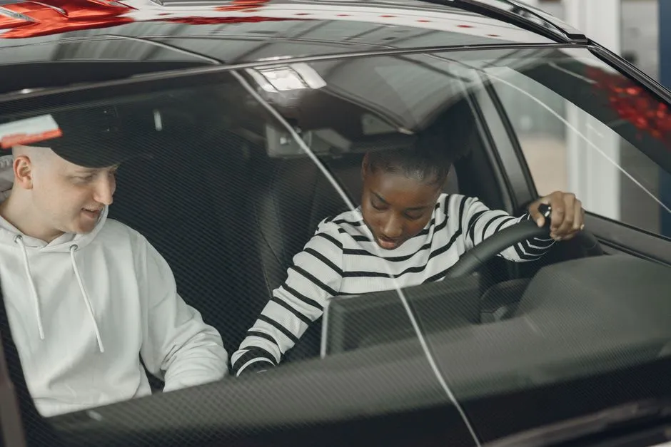 An instructor and a student talking in the front seats of a car