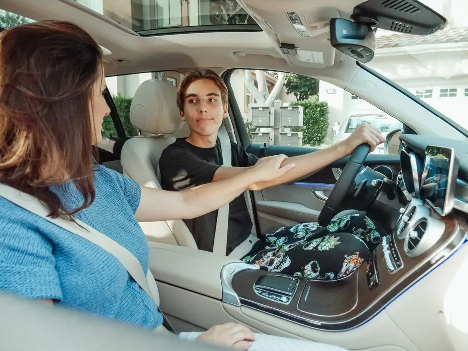 A parent in the passenger seat encouraging a teenager at the wheel